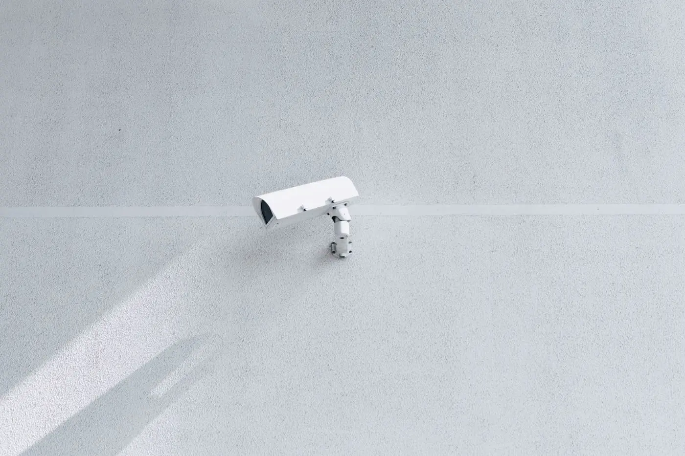 A camera mounted on a wall, facing a white wall. Illustrates the importance of digital security 